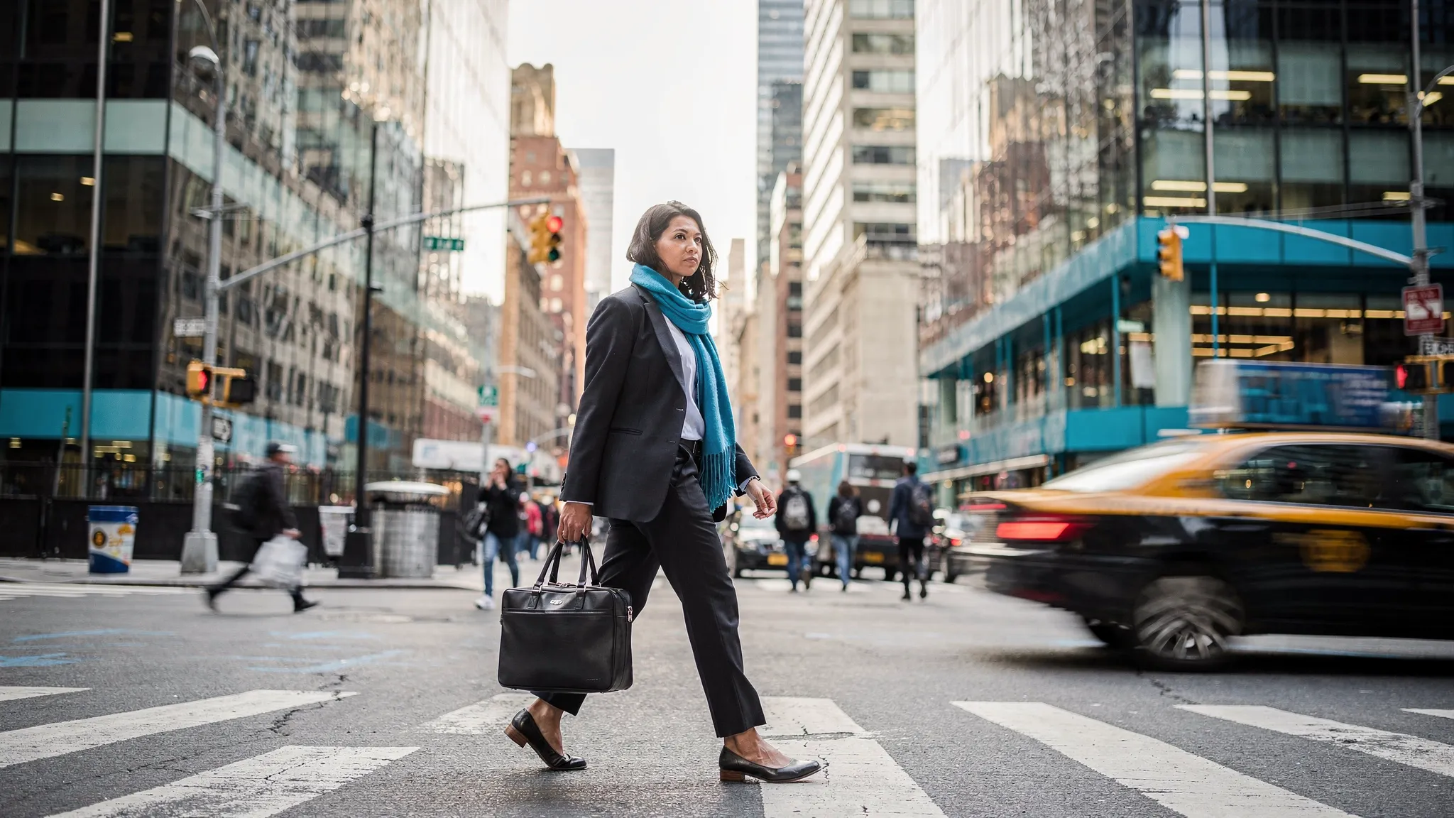 A busy New Yorker walking through Manhattan with a work bag, standing upright with relaxed shoulders, while city streets and office buildings surround them.